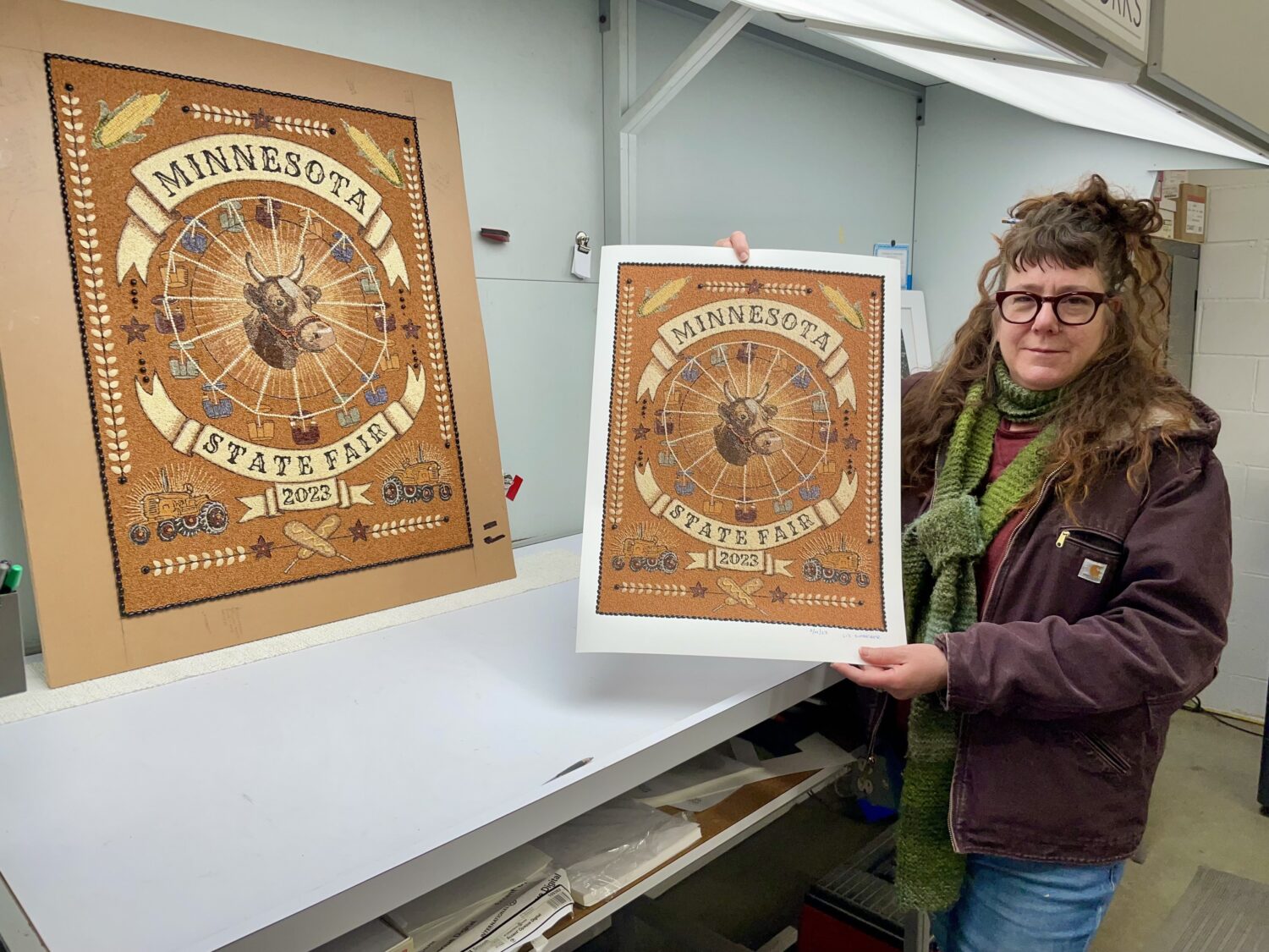 Liz Schreiber holding a print next to the original artwork.