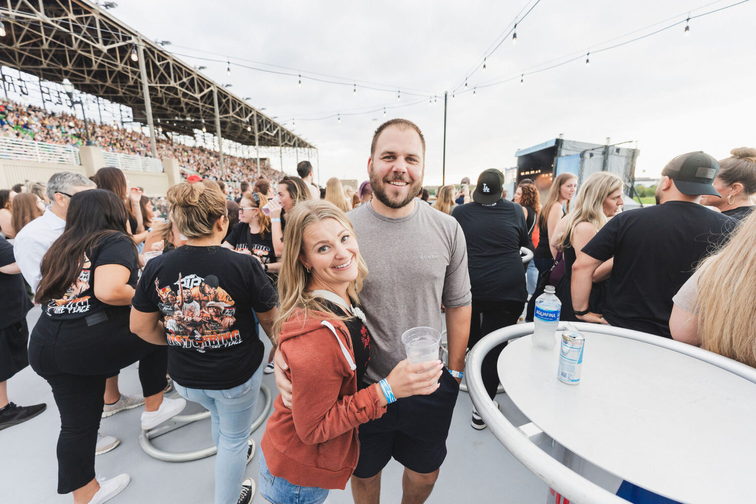 A couple on the party deck smiling and holding drinks at a high-top table.